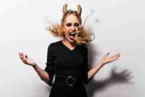 Free photo angry blonde witch standing on white background excited female model in halloween costume expressing emotions during photoshoot