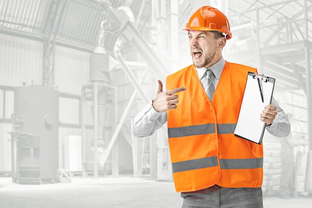 Free photo the angry builder in a construction vest and orange helmet screaming. safety specialist, engineer, industry, architecture, manager, occupation, businessman, job concept