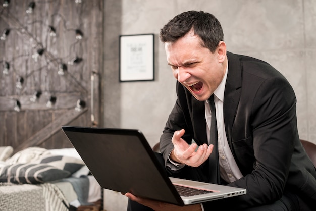 Free photo angry businessman yelling at laptop at home