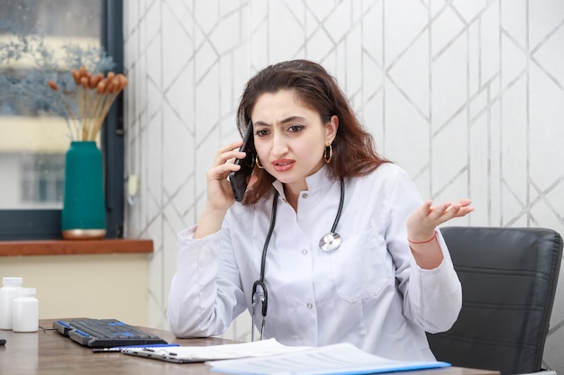 Angry doctor talking on the phone while sitting at the office High quality photo