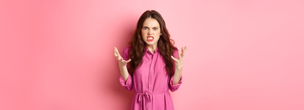 Angry and furious young woman shaking hands looks frustrated and outraged arguing complaining on som