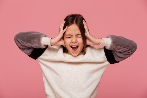 Angry girl screaming and holding head with hands isolated