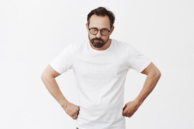 Angry and grumpy bearded mature man with glasses posing