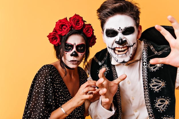 Free photo angry guy with mexican scary mask posing . stylish zombie couple fooling around in halloween.