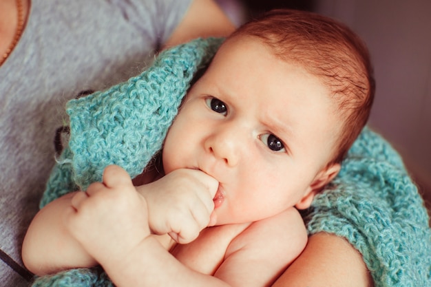 Angry little baby lies in mother's arms