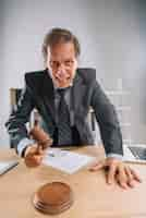 Free photo an angry mature male lawyer hitting mallet on sounding block in the courtroom