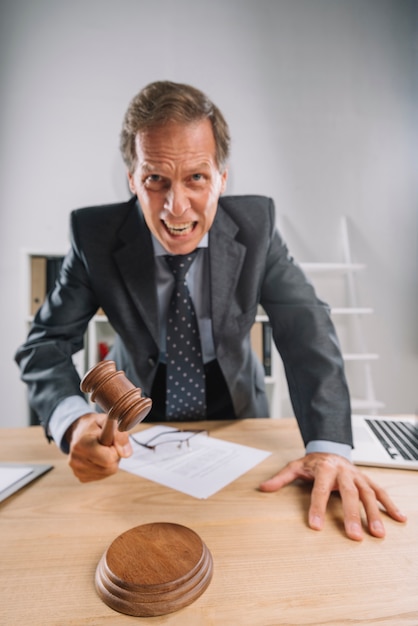 Free Photo an angry mature male lawyer hitting mallet on sounding block in the courtroom