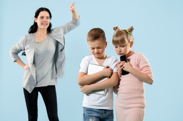 Free Photo angry mother scolding her son and daughter at home. studio shot of emotional family. human emotions, childhood, problems, conflict, domestic life, relationship concept