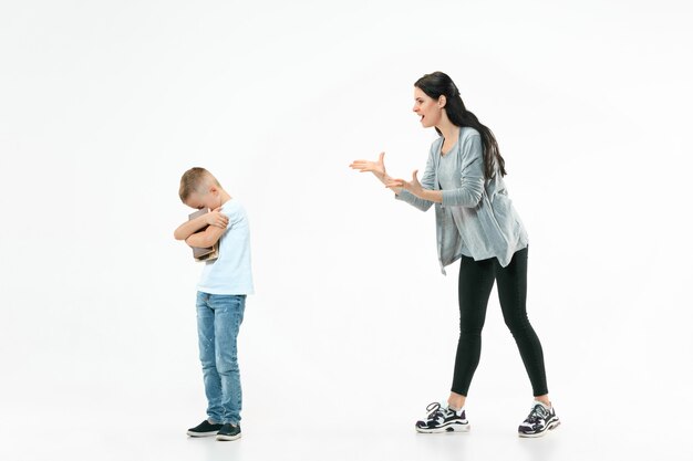 Angry mother scolding her son at home.