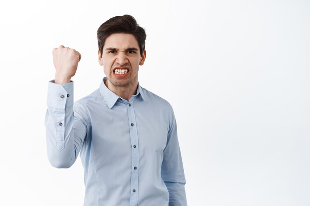 Angry office worker shaking fist in threaten, look outraged and pissed-off, standing frustrated against white background