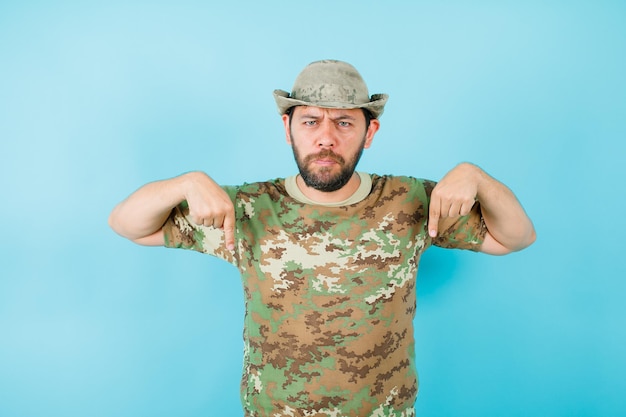 Free Photo angry officer is pointing down with forefingers on blue background