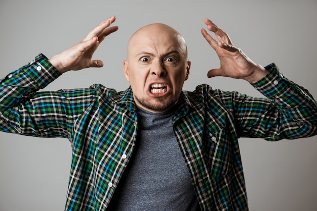 Free photo angry rage young man shouting over beige wall.