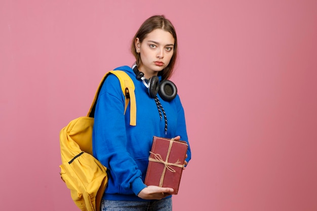 Angry schoolgirl standing holding bunch of old books