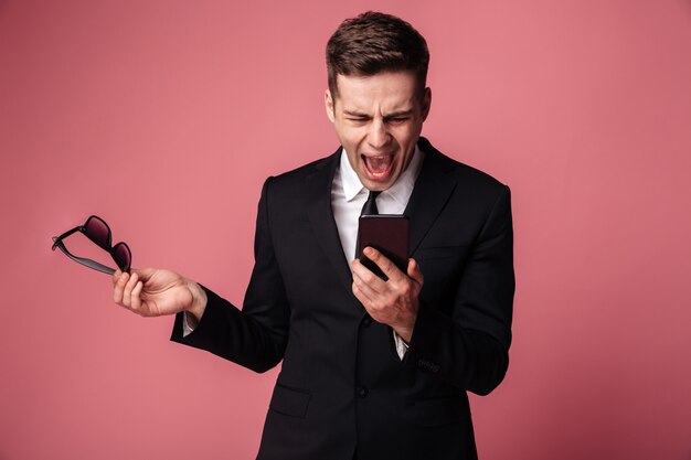 Angry screaming displeased young businessman talking by phone