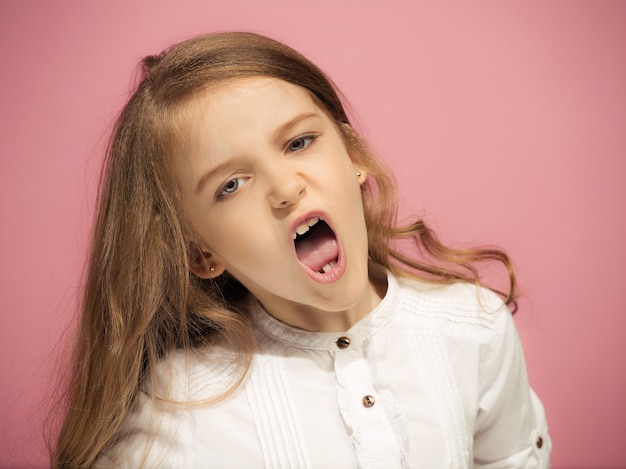 Angry teen girl standing on trendy pink. Female half-length portrait. Human emotions, facial expression concept