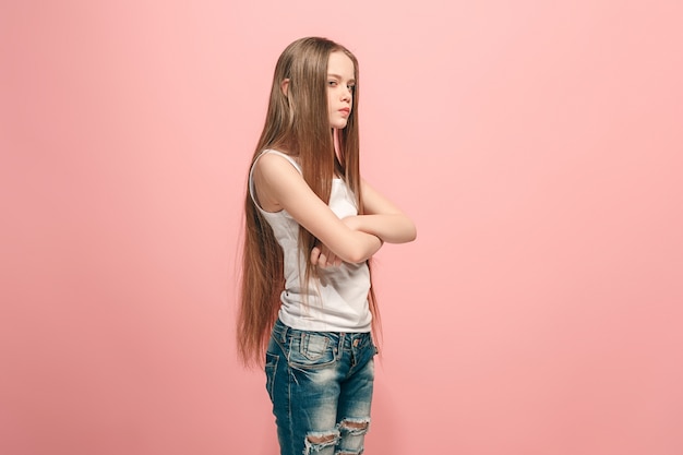 Angry teen girl standing on trendy pink. Female half-length portrait