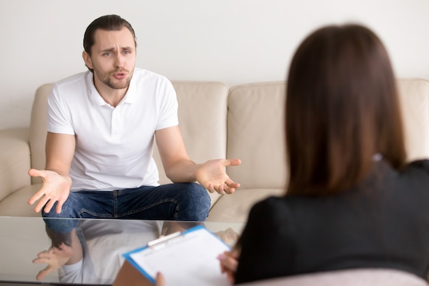 Free photo angry troubled man complaining to female psychotherapist, talking about problems