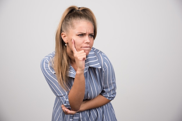 Angry woman looking at something on gray wall.