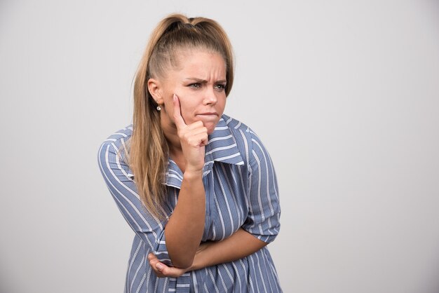 Angry woman looking at something on gray wall.