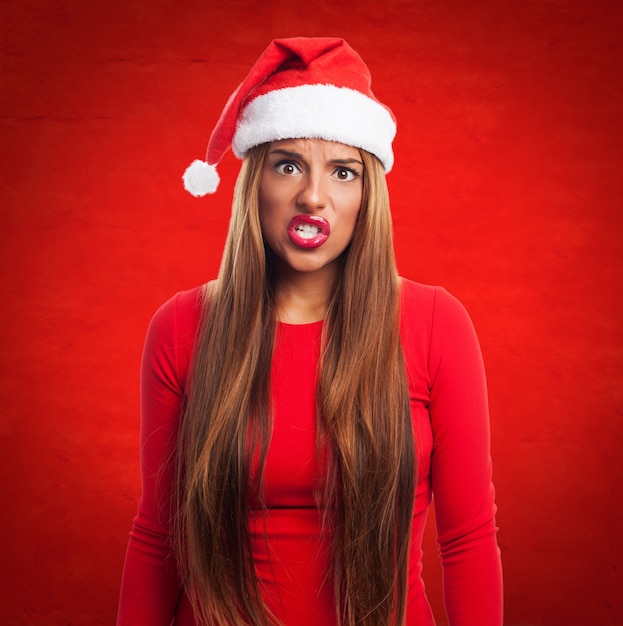 Angry woman with santa's hat in a red background