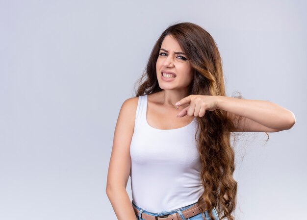 Angry young beautiful girl pointing straight  with copy space