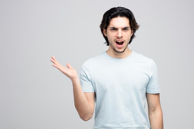 angry young handsome man looking at camera showing empty hand isolated on white background