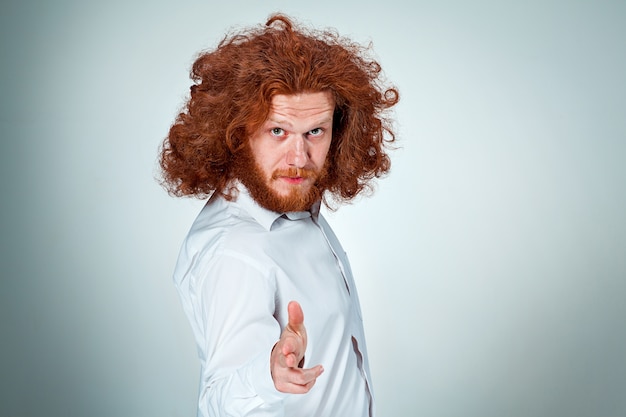 Free photo angry young man with long red hair taking aim in camera