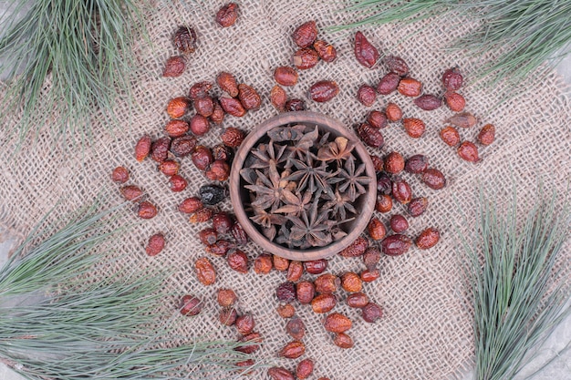 Free Photo anise in a wooden cup with dry hips around.