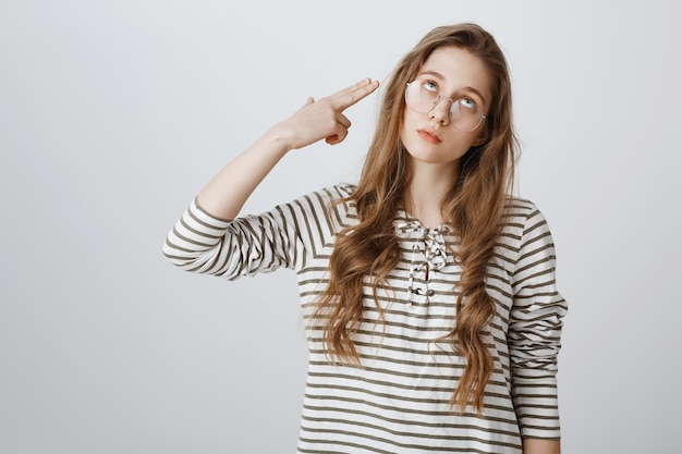 Annoyed girl roll eyes and shooting herself fake gun gesture, going nuts