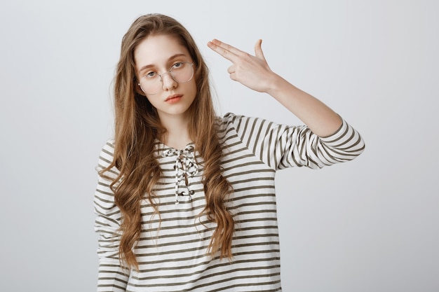 Annoyed girl roll eyes and shooting herself fake gun gesture, going nuts