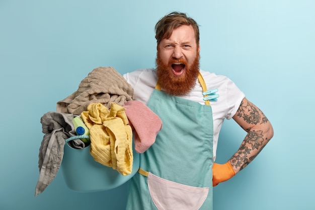 Free Photo annoyed housekeeper keeps hand on waist, shouts angrily, wears casual t shirt and apron