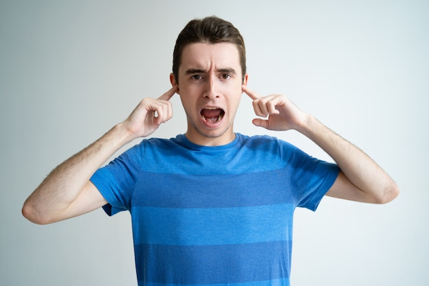 Free Photo annoyed man screaming and stopping ears with fingers