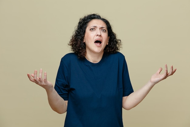 Free photo annoyed middleaged woman wearing tshirt looking at camera showing empty hands isolated on olive green background