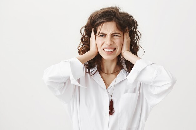 Annoyed pissed-off woman shut ears from loud noise