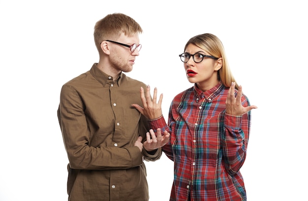 Free photo annoyed pretty girl in cat eyeglasses and plaid shirt gesturing with both hands, expressing her indignation while being mad at her clueless boyfriend who forgot about their anniversary again