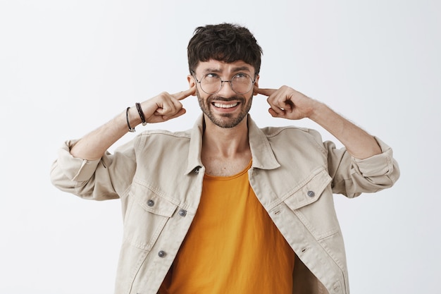 Annoyed stylish bearded guy posing against the white wall