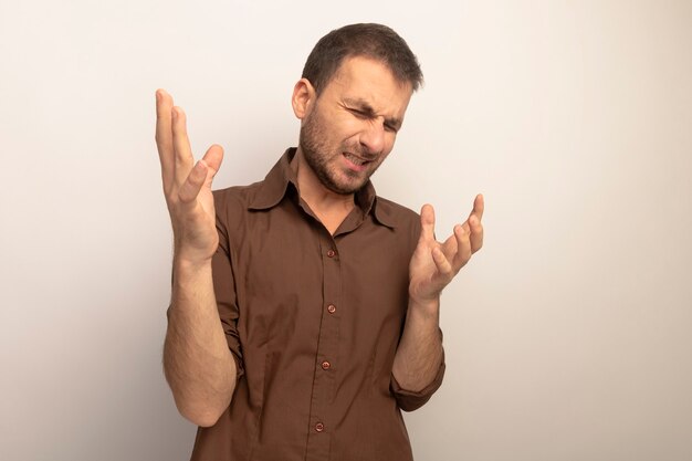 Annoyed young caucasian man keeping hands in air with closed eyes isolated on white background with copy space