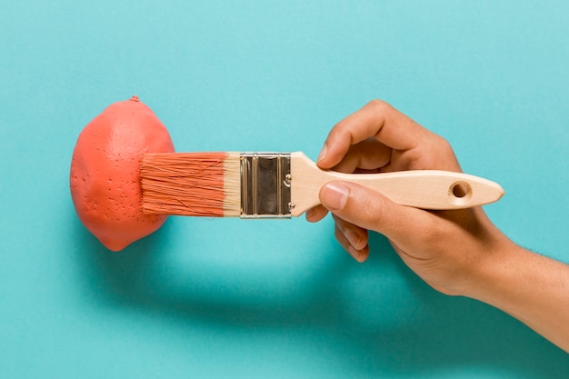 Anonymous artist painting lemon in pink color