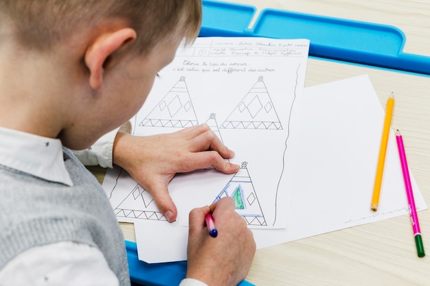 Free photo anonymous boy coloring pictures during lesson