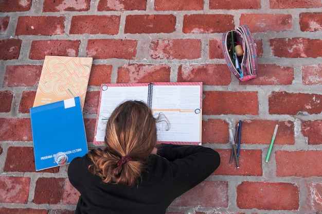 Free Photo anonymous girl studying on brick pavement