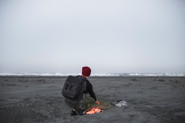 Free photo anonymous man warming near fire