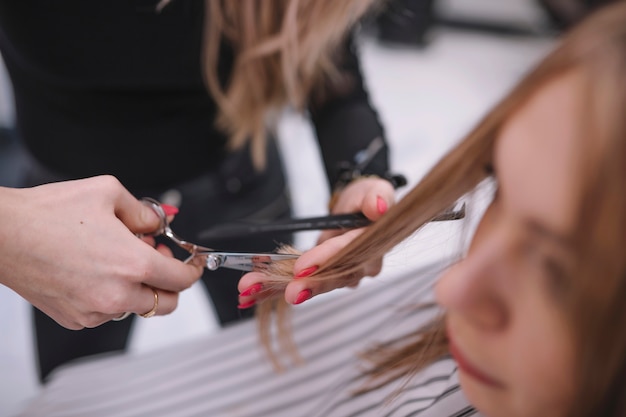 Free photo anonymous stylist trimming hair ends