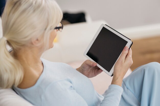 Anonymous woman browsing tablet on couch