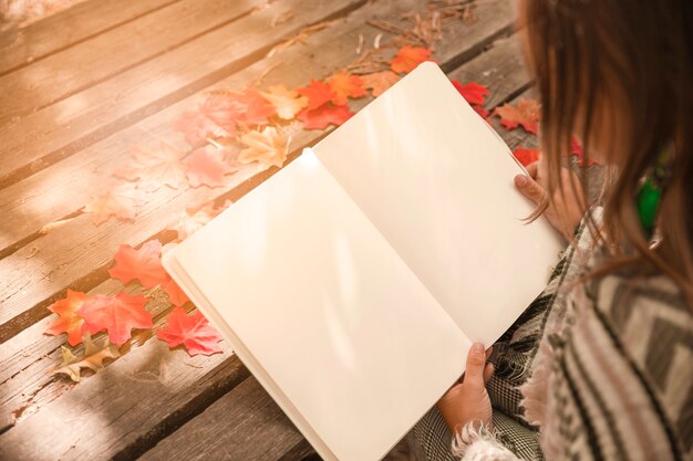 Anonymous woman reading book in autumn park