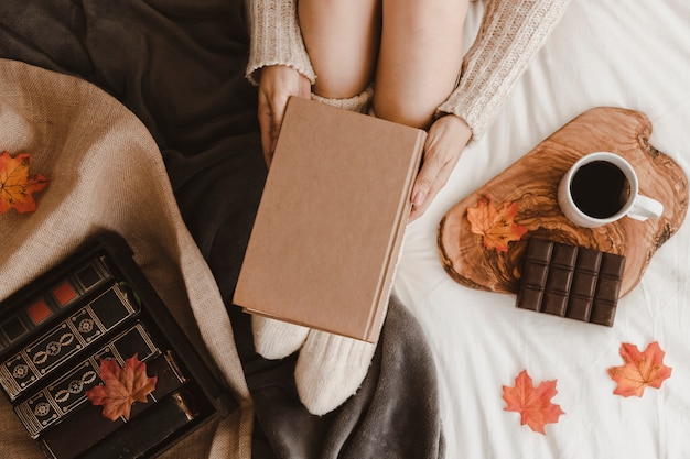 Free photo anonymous woman with book near tea and chocolate