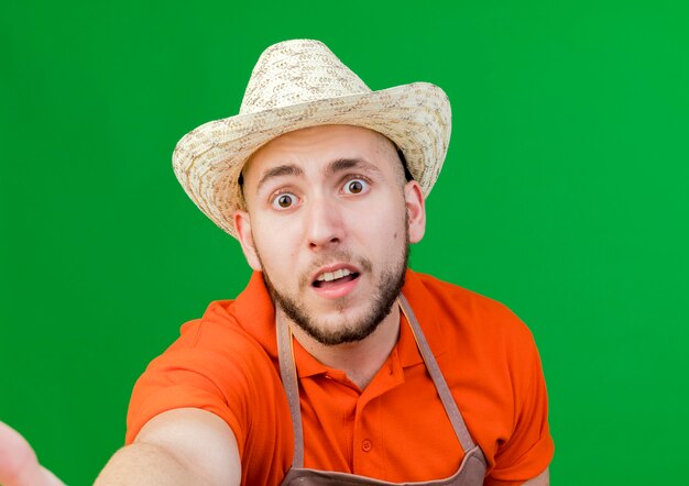 Anxious gardener man wearing gardening hat pretenfd to hold and looks  