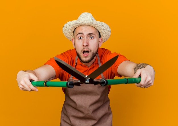 Free photo anxious male gardener wearing gardening hat holds garden clippers