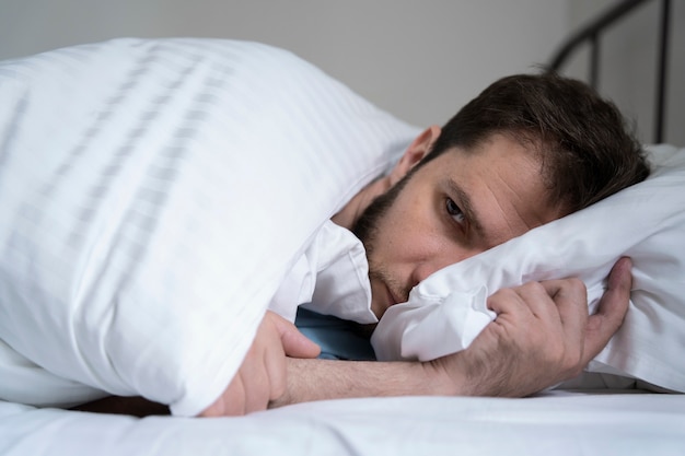 Anxious man laying in bed medium shot