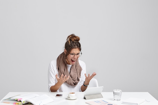 Free photo anxious woman looks at tablet, realizes that she didn`t save project and should do everything from beginning