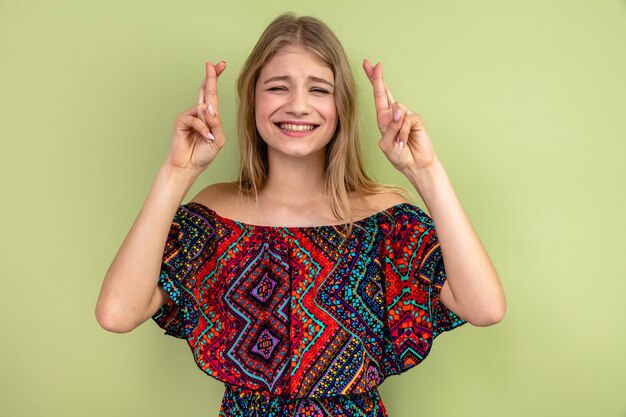 Anxious young blonde woman crossing her fingers 